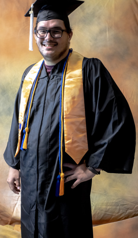 Photo is of me wearing my cap and gown, also with a stole and cords that represent Phi Theta Kappa colors, blue and gold.