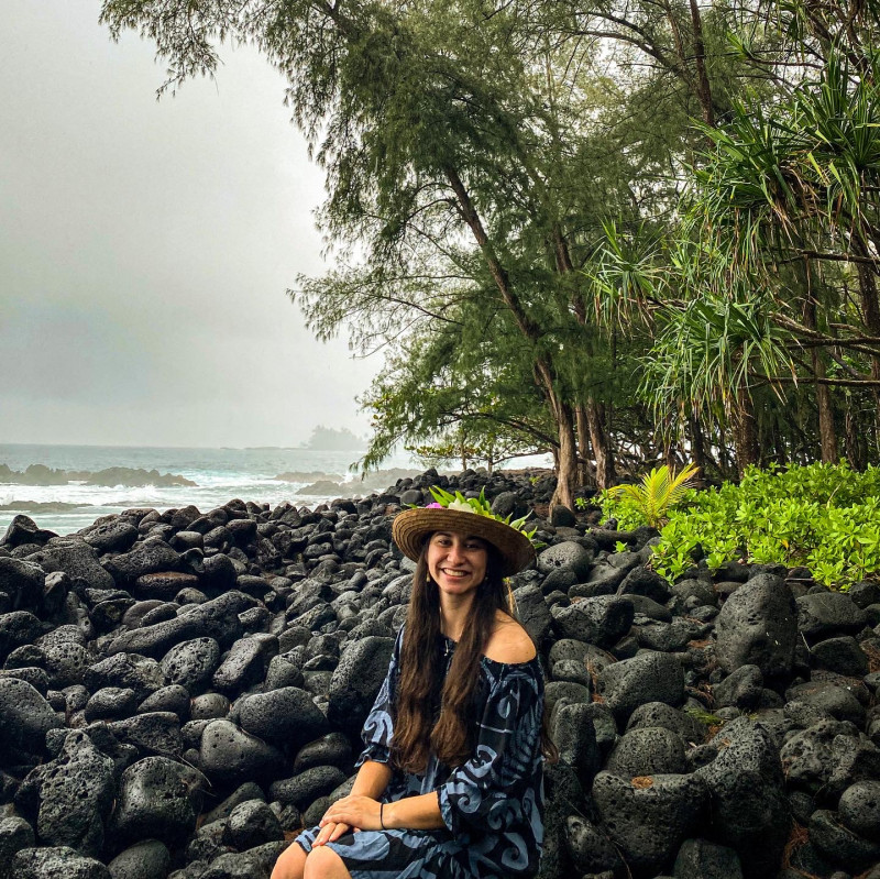 Image of Brianna (graduate) sitting on a rocky shoreline.