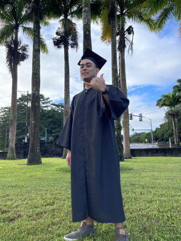 Standing in front of campus in regalia