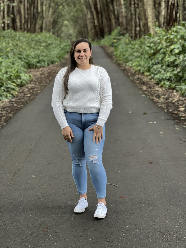 Wearing a white sweater with jeans. Surrounded by tall trees with my hair down and a nice smile.
