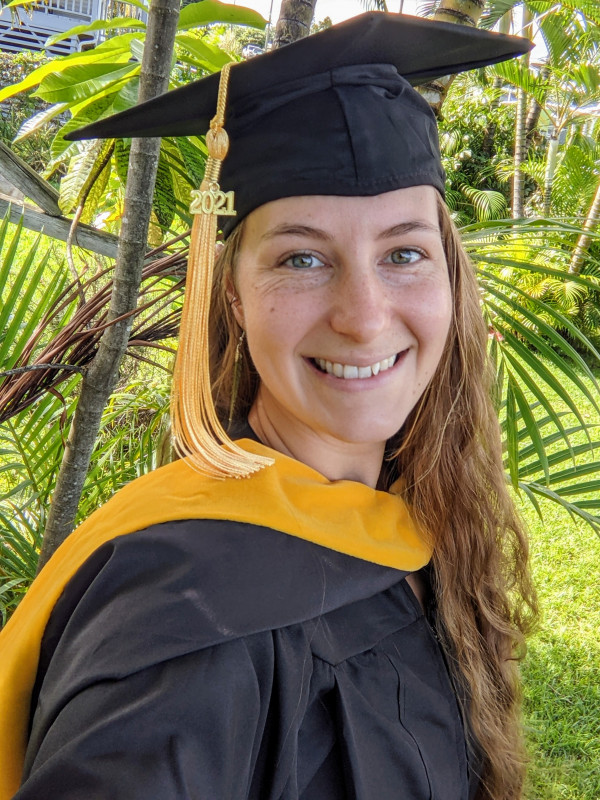 My in my master's regalia in front of some of the palms and ferns in my yard
