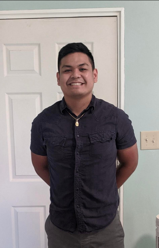 Picture of myself in a buttoned up shirt, with a gold chain. Background has an aqua blue color.