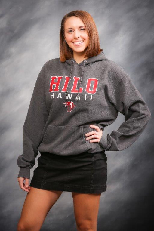 Photograph of Rachel standing in front of grey background with one hand on her hip and she is wearing Hawaii Hilo sweatshirt and black skirt.