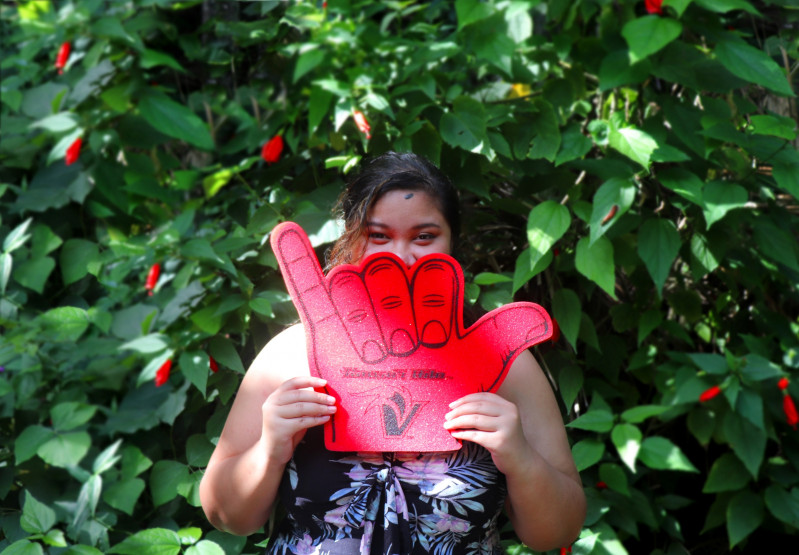 posing with a foam shaka in front of my face with a red and green natural backdrop