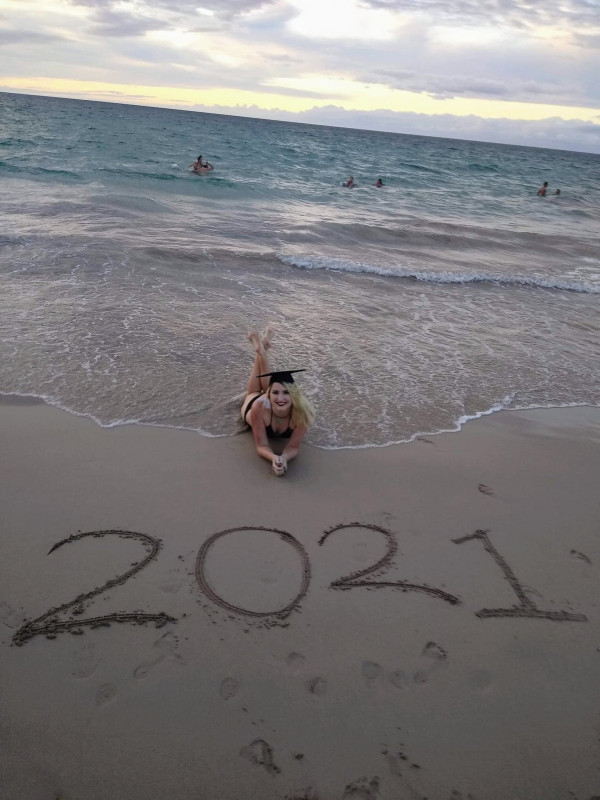 laying on beach in bikini and graduation cap with "2021" writen infront of me