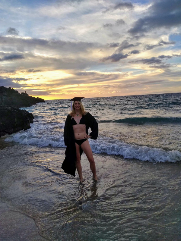 Standing on beach during sunset in bikini and graduation cap