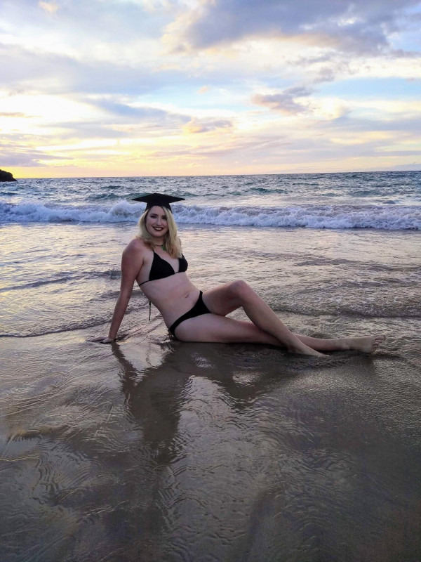 Sitting on beach durring sunset in bikini and Graduation cap