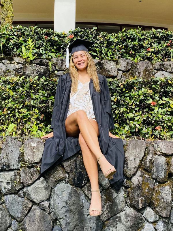 Me sitting down on the rock wall in my cap and gown