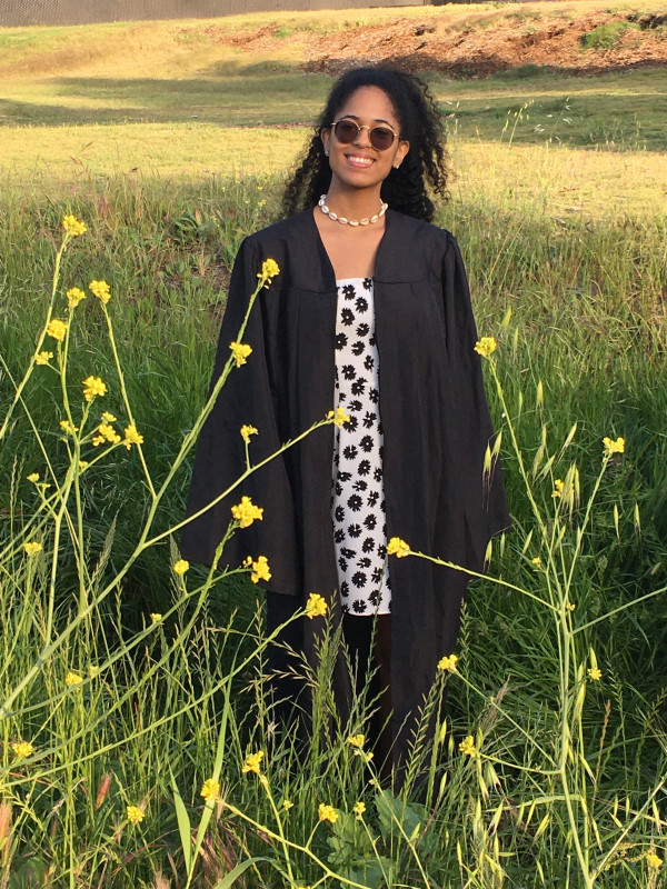 A girl smiling in tall grass. She is standing.