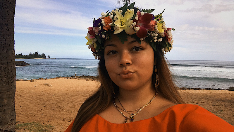 This is a photo of me at the beach wearing a red and yellow puletasi.