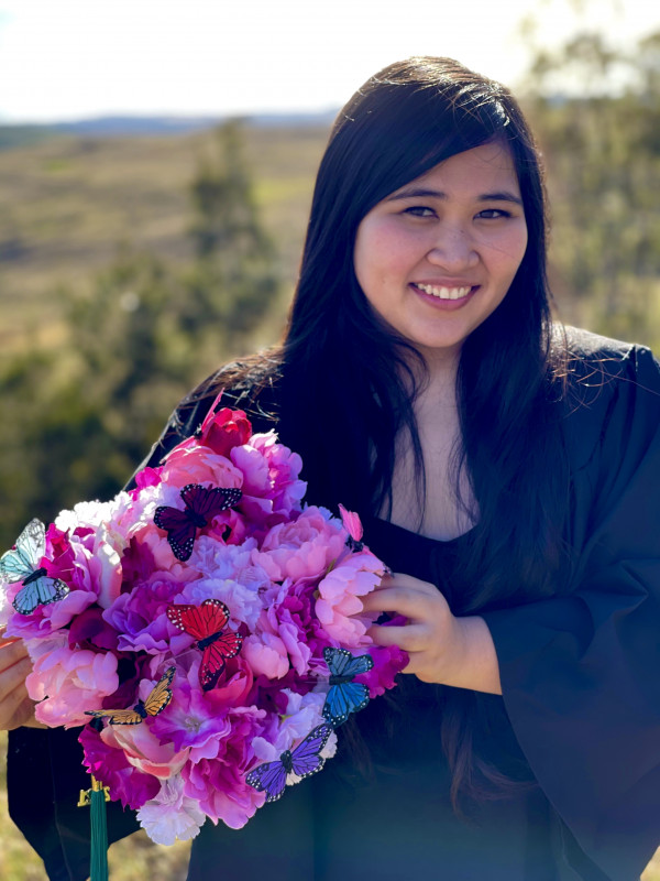 A headshot picture of me in my graduation attire with my decorated cap (flowers and butterflies)