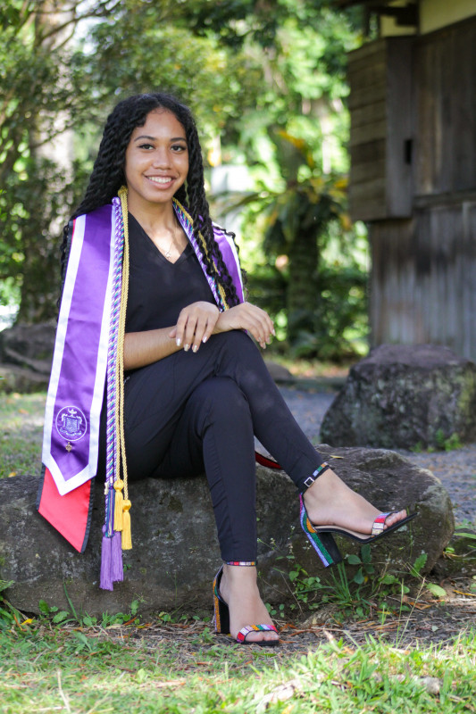 Graduate sitting in black scrubs