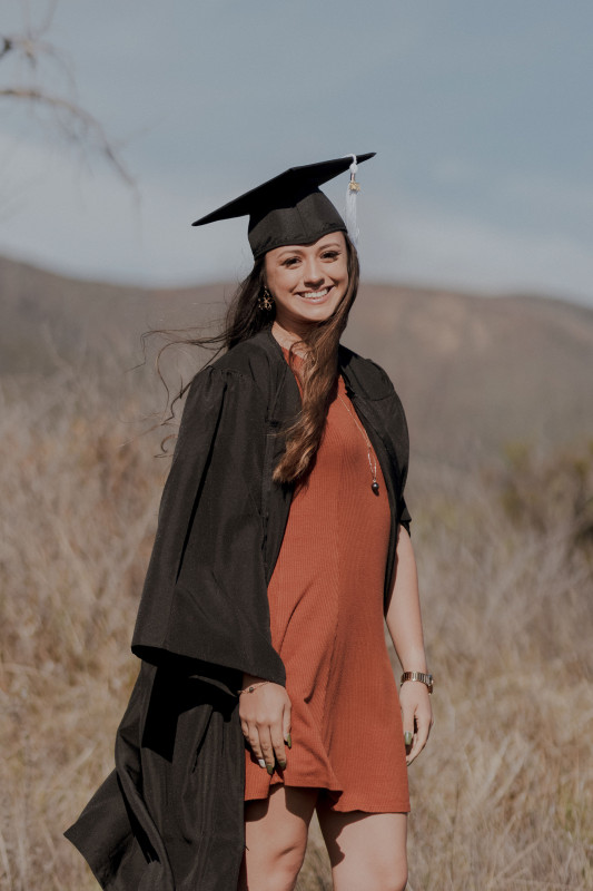 I am in a burnt orange dress with my cap and gown. The image is from my knees up.