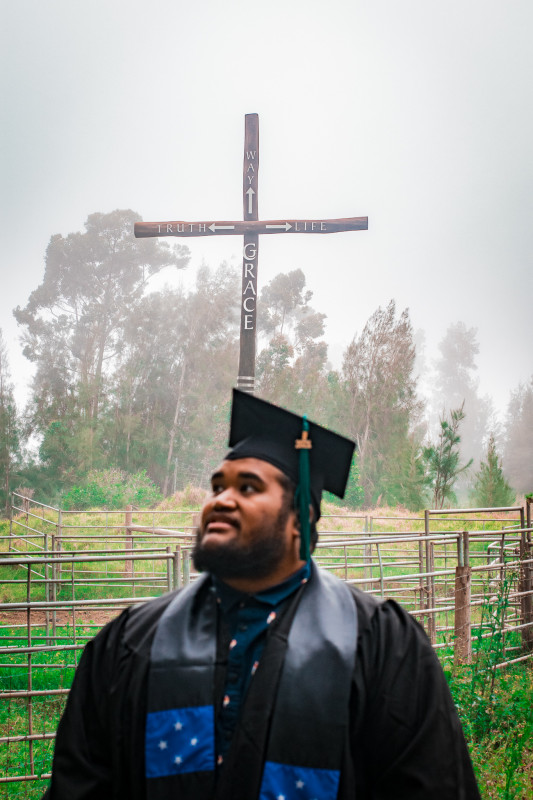 standing in full attire infront of a cross