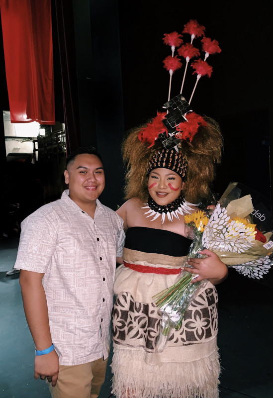 This photo was taken at the UH at Hilo theatre/ Performing Arts Center after I performed for International Night 2020 with the Samoan TOS (Tupulaga O Samoa) Club . I am dressed in traditional Samoan attire on the stage after the show holding bouquets of flowers, posing next to my boyfriend.