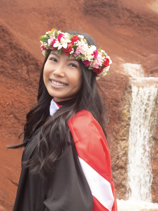 Elvie Rose Bisarra standing in front of a waterfall located in Kaua'i, which is known for its red soil.