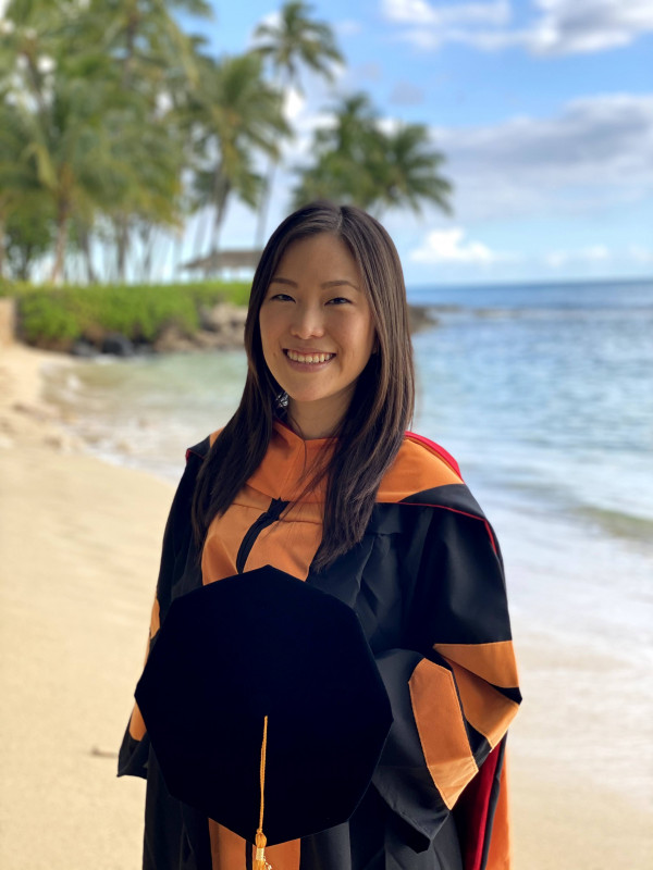 Graduate standing on the shoreline.