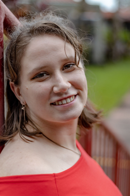 Headshot of Sienna Wareham leaning against a red pole