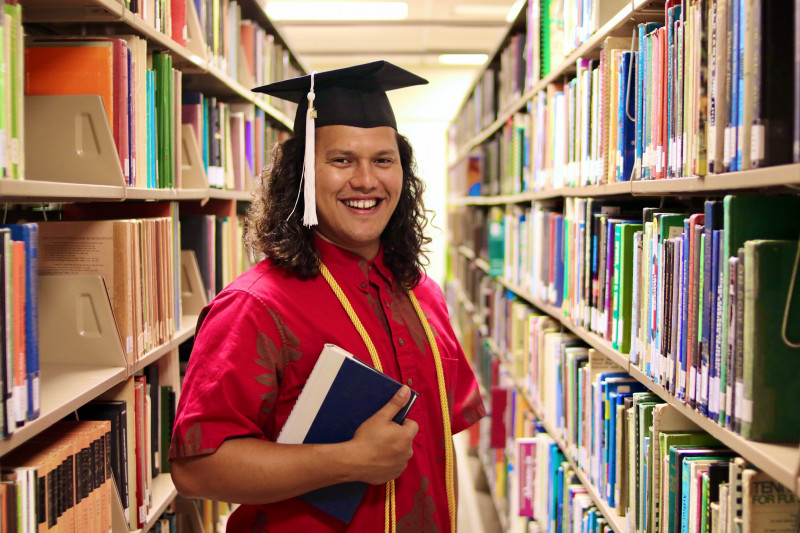 My fourth photo is of me holding a book in my arm standing between two rows in the library.