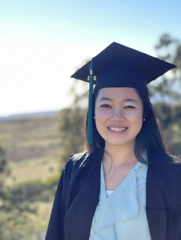 A portrait photo of myself with my cap and gown against a blue-sky backdrop.