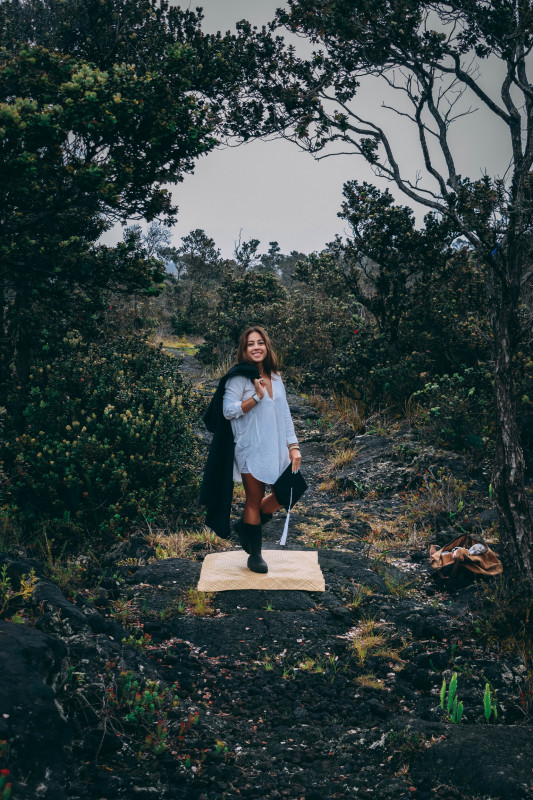 Kaitlyn in an ʻohiʻa forest holding her cap and gown.