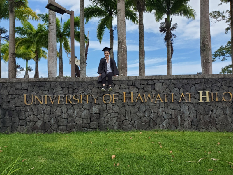 Sitting on the UH Hilo rock wall and smiling