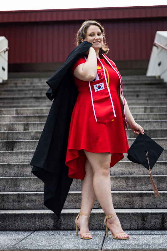 Sienna Wareham standing on some stairs holding her cap and gown