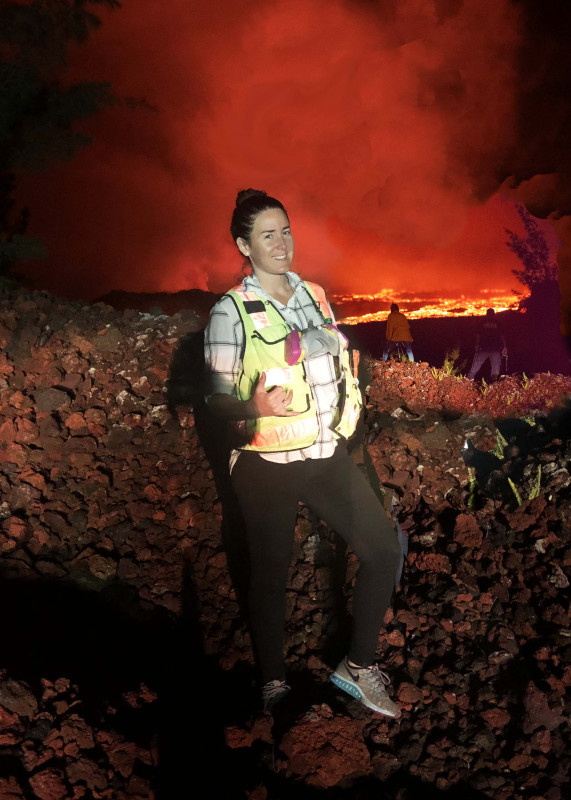 Michelle Mazzetti standing in front of a huge river of A'a Lava as it is flowing down around Green Mountain into Kapoho