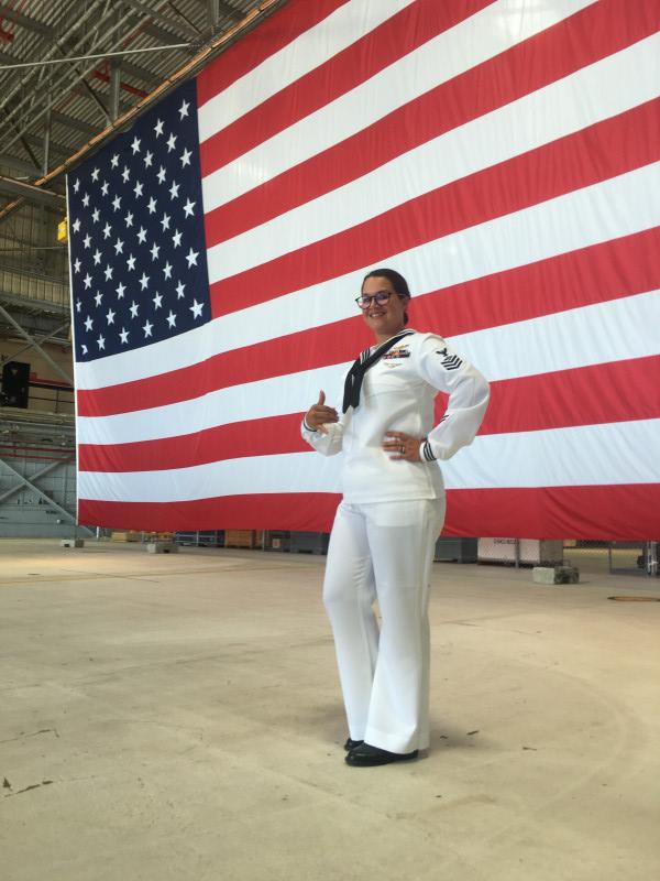 Standing in front of a big American flag in my dress whites giving a Shaka