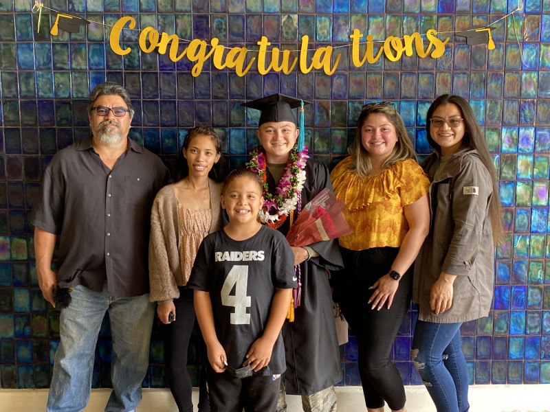 self dressed in cap and gown with family