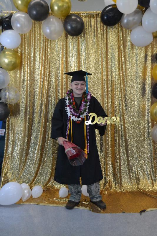 Self dressed in cap and gown, holding a done sign
