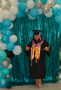 A picture of me in my cap and gown throwing the shaka.