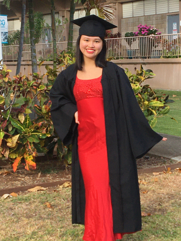A close up shot of a person wearing a cap and gown, with a bright red dress.