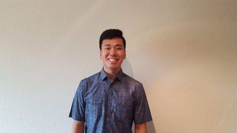 A charming young charismatic young man in a button-up with a white background