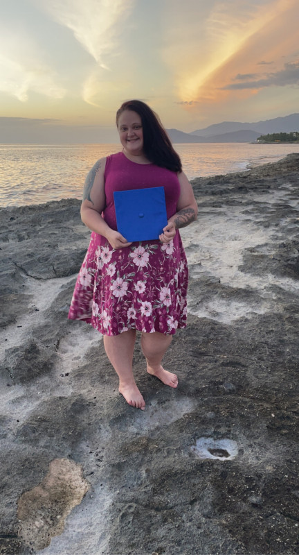 College grad by the ocean with sunset