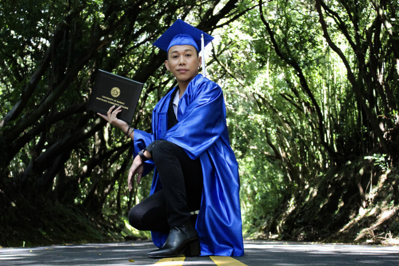 Jiro Manog wearing his cap and gown and showing off his dipolama from Kapiolani Community College.
