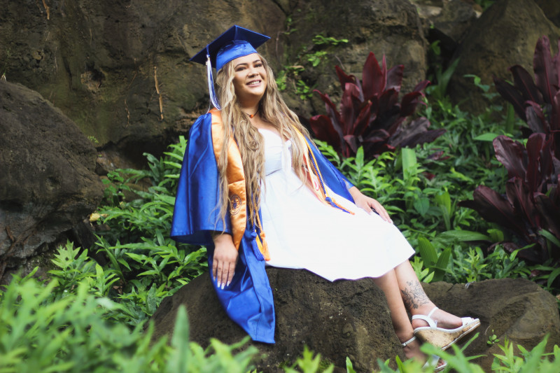 Kiana posing on a rock with her cap and gown.