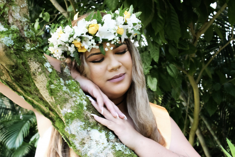 Kiana posing in her haku lei on a tree branch.