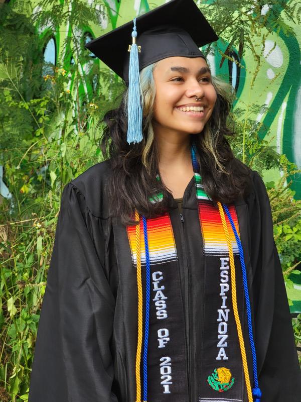 Elena in their cap and gown smiling with joy.