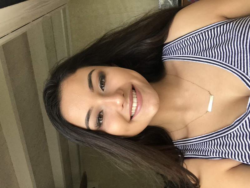 Me smiling with makeup in a striped tank top and hair down