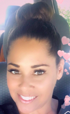 Headshot of a female who has her hair up in a bun with images of hearts on the side