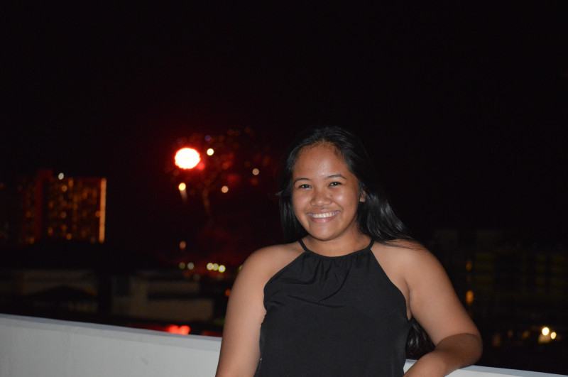 A photo of myself in a black romper with fireworks in the background.