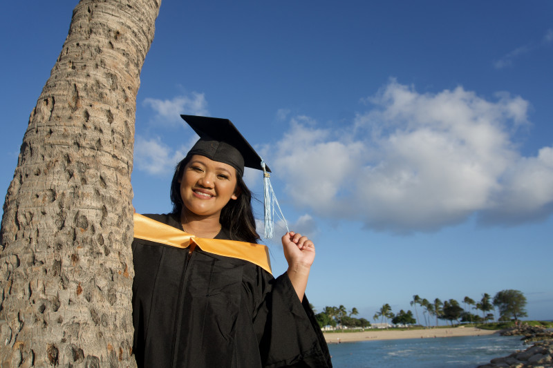 This picture is taken by the beach as well. It shows my frontal view smiling with my cap, gown, and me holding my tassel with my left hand. Beside me is a tree.