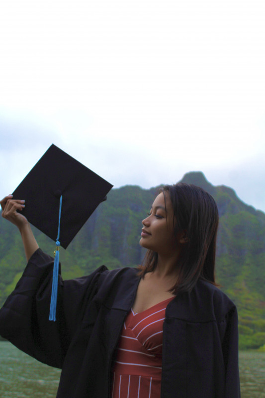 A picture of me  holding my cap  and wearing my black gown with a Mountain View.