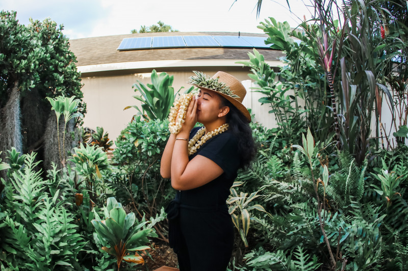 A girl smelling a puakenikeni lei