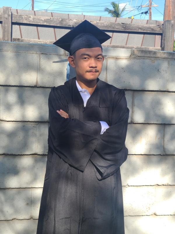 It's a picture of myself in my cap and gown outfit looking into the distance while also having my arms crossed.