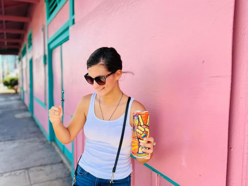 Morgan standing in front of a bright pink wall smiling and holding a tea