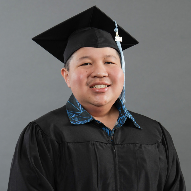 Headshot of me with cap and gown on smiling