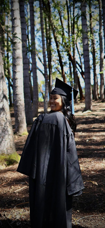 body position on the side while facing the camera wjile wearing gown on shoulders and have the cap and tassel on the head