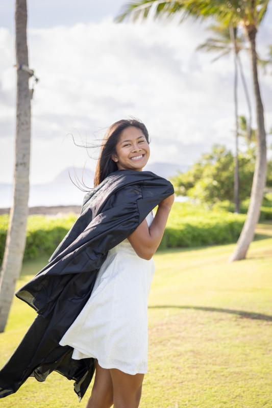 Smiling with cap and gown at the beach